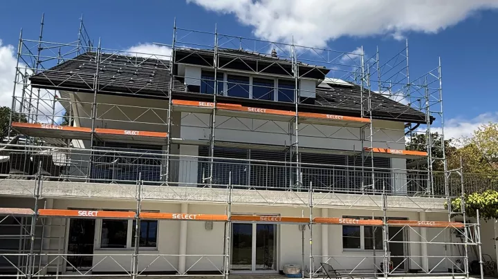 Maison individuelle entourée d'échafaudages pendant des travaux de rénovation extérieure