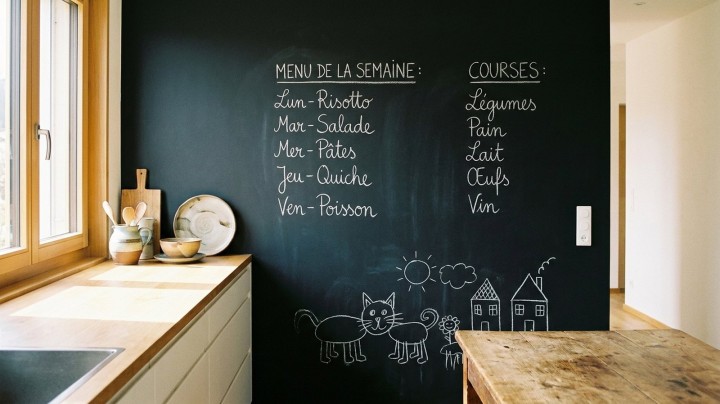 Mur de cuisine peint en peinture tableau noir, avec le menu de la semaine et la liste de courses écrits à la craie