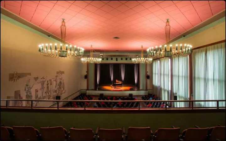 Salle de spectacle de Renens vue du balcon, plafond saumon et lustres en cristal au-dessus des fauteuils