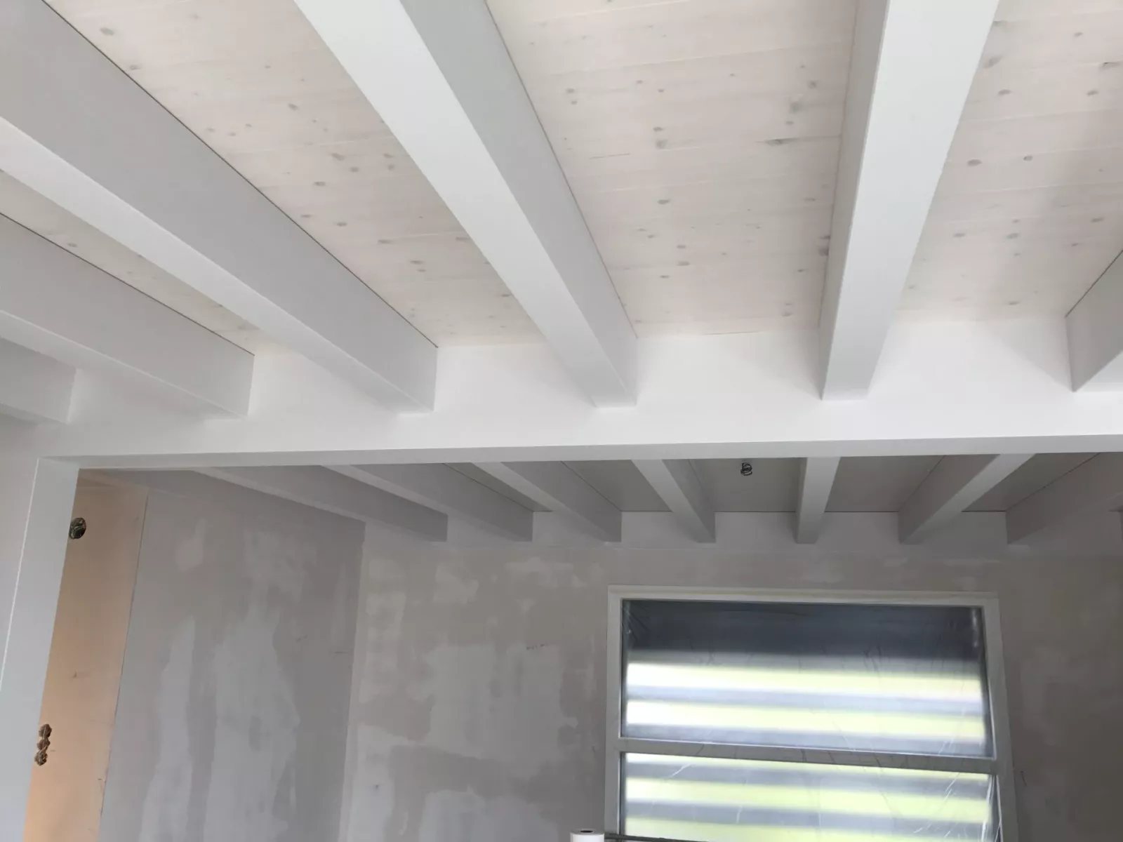 Plafond en lambris et poutres peint en blanc dans l'ancienne ferme rénovée