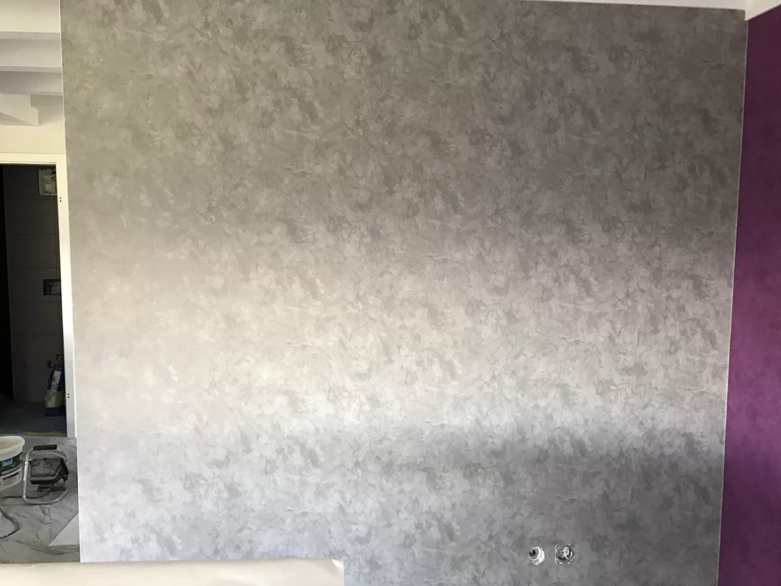 Mur fini en enduit décoratif effet nuagé gris argenté, bordé d'un pan de mur prune