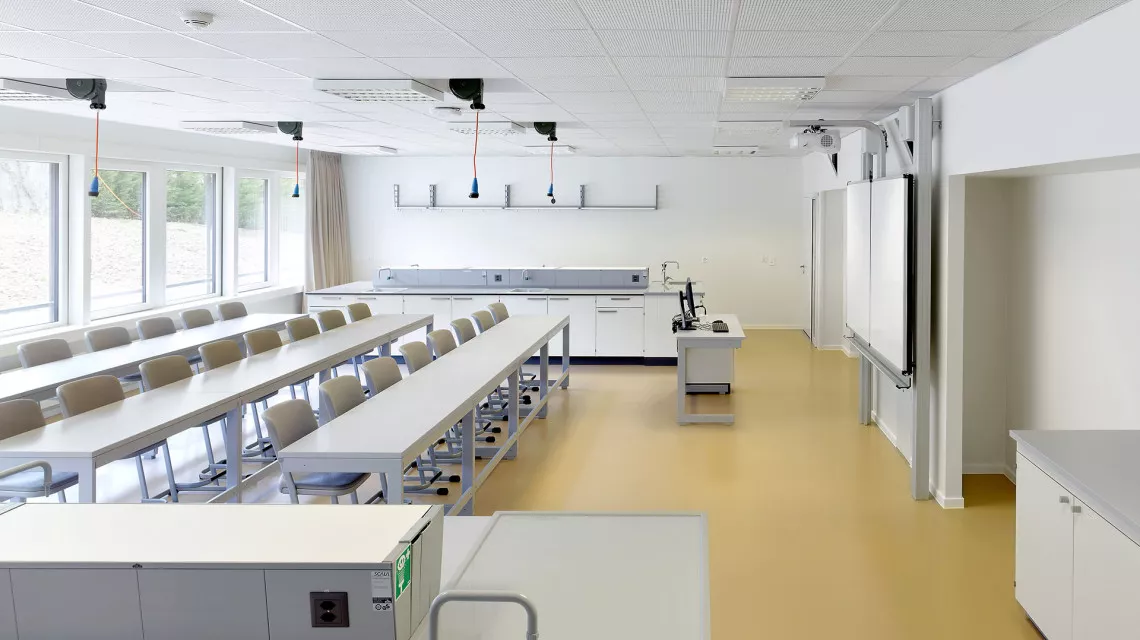 Salle de classe de l'International School of Lausanne avec ses longues tables blanches et son sol beige