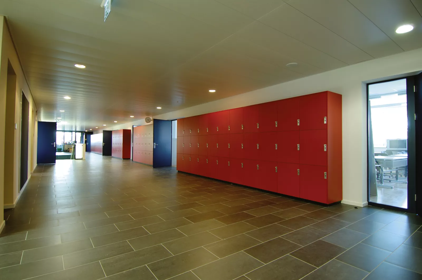 Couloir de l'International School of Lausanne bordé d'une longue rangée de casiers rouges