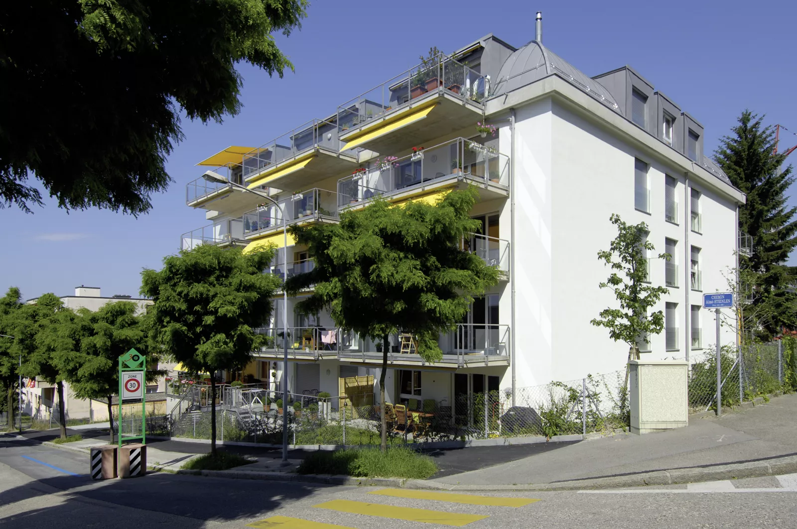 Immeuble des Balcons de Vallombreuse aux stores jaunes, vu depuis la rue bordée d'arbres