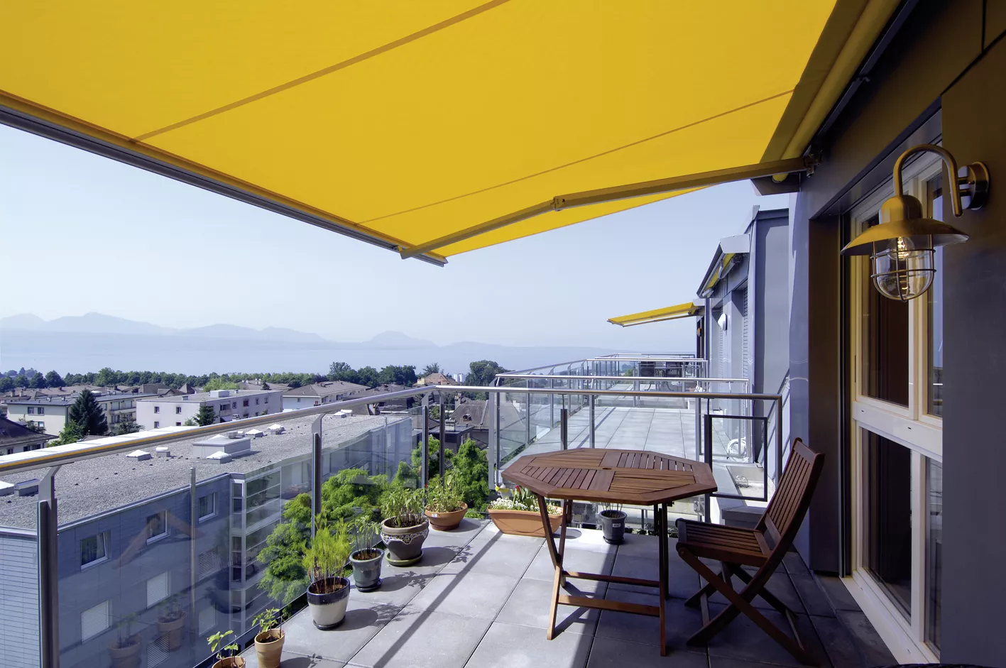 Terrasse des Balcons de Vallombreuse sous un store jaune, avec vue sur le lac