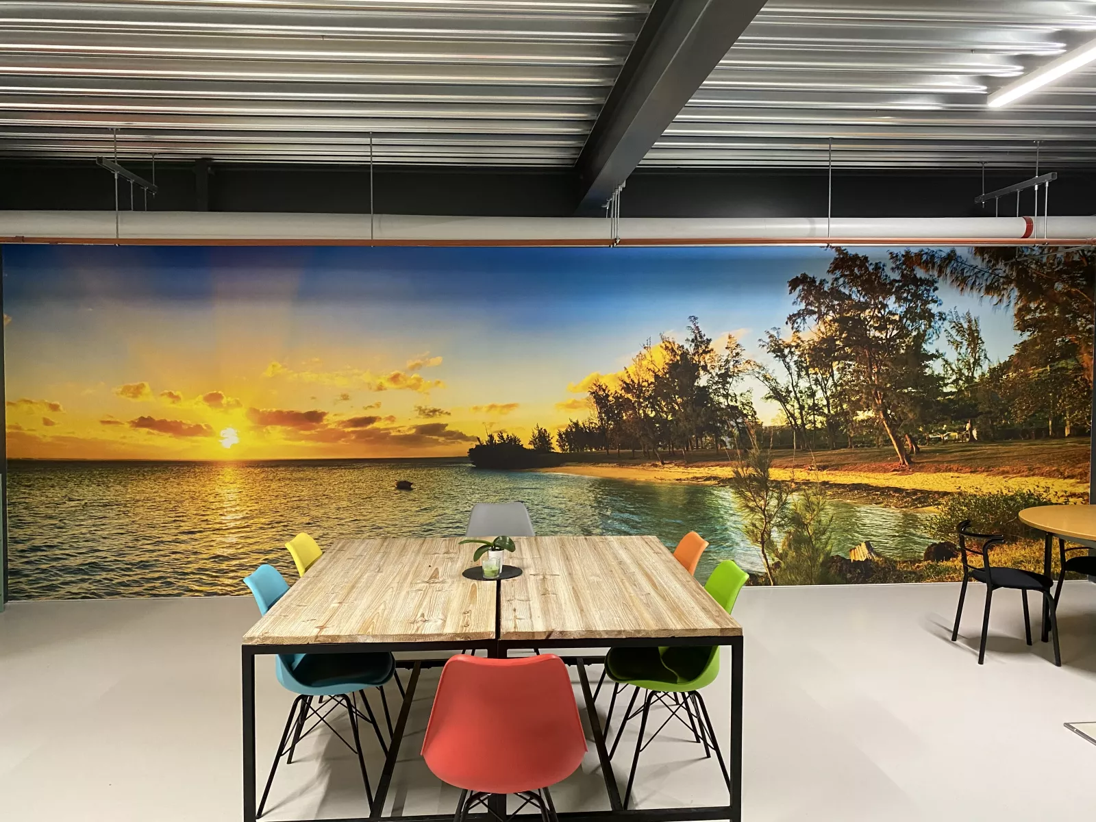 Salle de pause de l'atelier G. Pucci SA, mur imprimé d'un panorama de plage et grande table de réunion