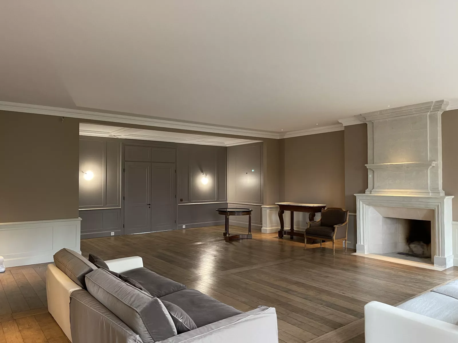Salon de la maison de maître avec sa cheminée en pierre et son parquet, après rénovation