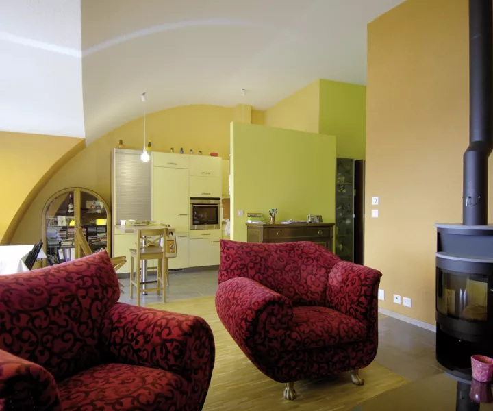 Séjour des Balcons de Vallombreuse, mur ocre voûté, cuisine vert anis et poêle à bois