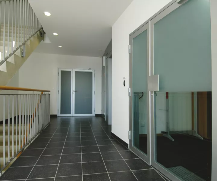 Palier carrelé de la résidence Sablons A avec porte vitrée et escalier