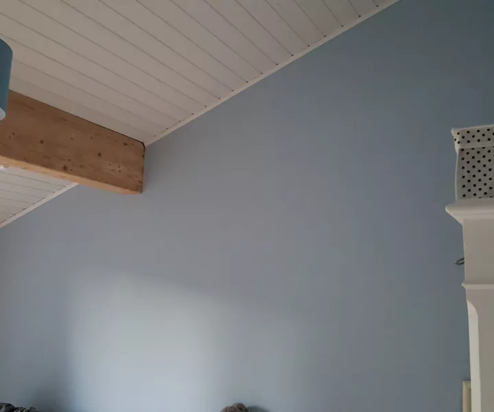 Chambre peinte en bleu-gris sous un plafond lambrissé blanc et une poutre apparente