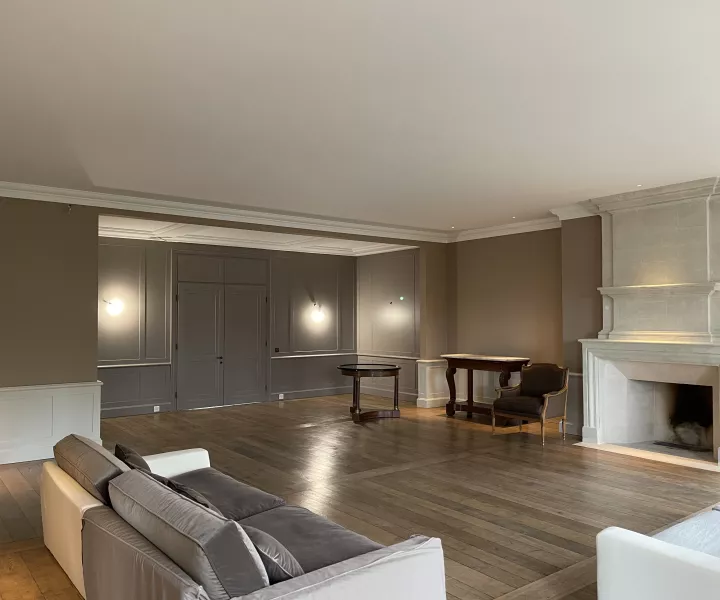 Salon de la maison de maître avec sa cheminée en pierre et son parquet, après rénovation